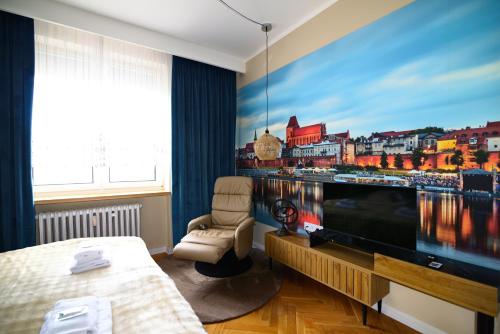 a bedroom with a large screen tv and a bed at City Stay Kaszownik AC Progres in Toruń