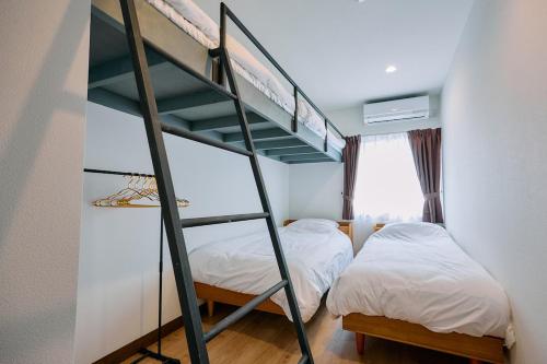 two beds in a room with a bunk bed at Tood一宮 -E棟 in Ichinomiya