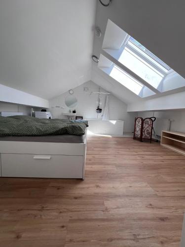 a white bedroom with a bed and a skylight at Vogelsang Apartments in Gmunden