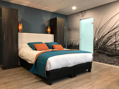 a bedroom with a bed with blue and orange pillows at Rivers Hotel in Sluis