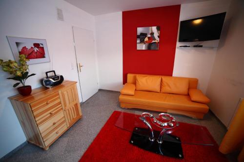 a living room with an orange couch and a red wall at Domki Cztery Pory Roku in Czchów