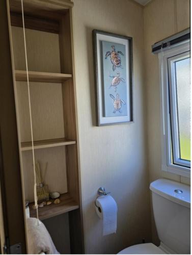 a bathroom with a toilet and a picture on the wall at Seabreeze in Goodrington
