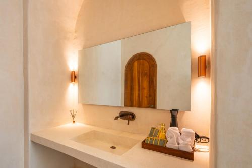 a bathroom with a sink and a mirror at Holista Bali in Kubupenlokan
