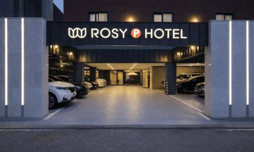 a hotel with a parking lot with cars parked at Cheonan Asan Rosy Hotel in Asan