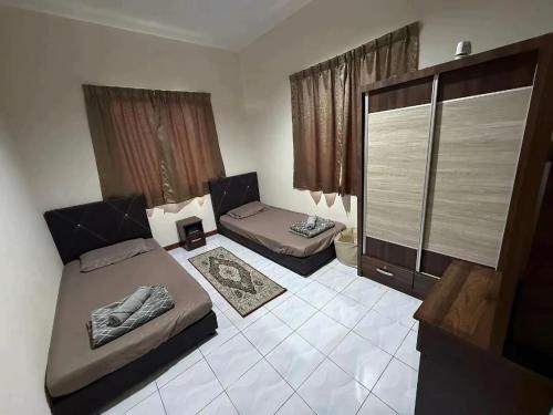 a small bedroom with two beds and a window at KRPV Homestay in Tambunan