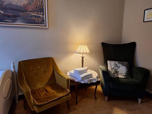 a room with two chairs and a table with a lamp at Tjøtta Gjestegaard in Alstahaug