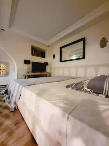 a bedroom with a large white bed and a television at Mediterranean Breeze Studio in Sidi Bou Saïd