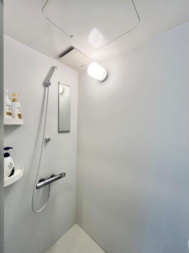 a shower in a bathroom with a white wall at Hotel Suite1 Quiet Family Stay Near Tokyo in Warabi