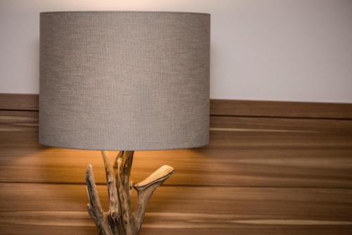 a table lamp with a driftwood lampshade on a wooden floor at Hotel Pinei in Ortisei