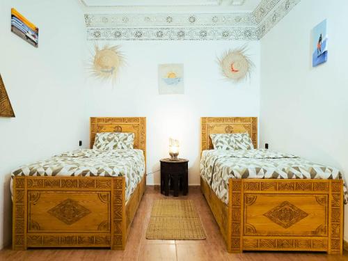 two beds in a room with white walls at Sunset Surfhouse Morocco in Tamraght Ouzdar