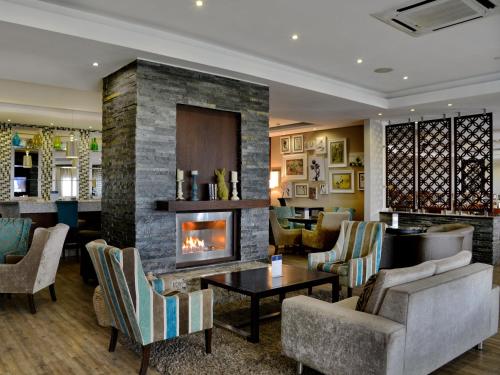 a living room with a fireplace and a table at ANEW Hotel Capital Pretoria in Pretoria