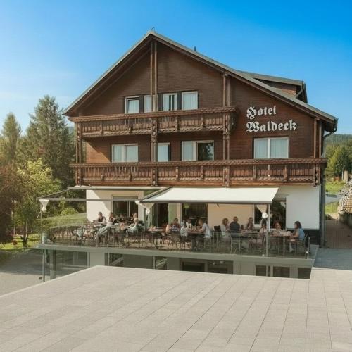 a large building with people sitting on a patio at Hotel Waldeck mit Restaurant "Florian'S" in Feldberg