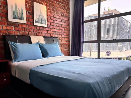 a bed with blue pillows in a room with a brick wall at Above A Shoplot No Noise Worries 12Pax & FreeWiFi in Ipoh