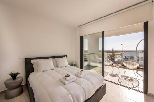 a bedroom with a large white bed and a balcony at Lake View Suites in Paralimni