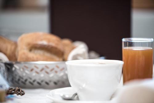 a table with a cup of coffee and a bowl of bread at Hotel Pinei in Ortisei