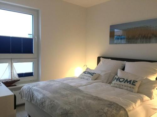 Schlafzimmer mit einem Bett mit weißer Bettwäsche und Kissen in der Unterkunft Apartment Warnemünde 15 in Warnemünde