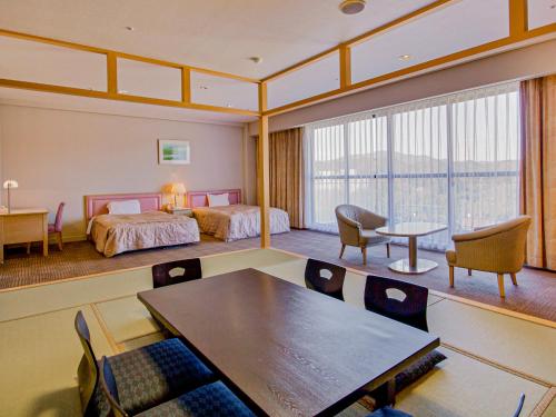 a room with two beds and a table and chairs at 汐の丸 in Imabari