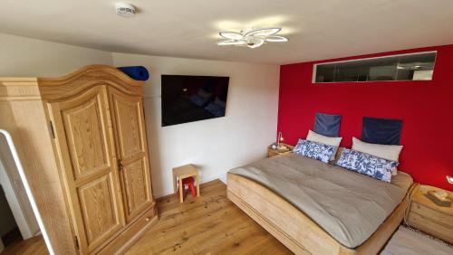 a bedroom with a bed with a red wall at Ihre exklusive Auszeit im Allgäu in Scheidegg