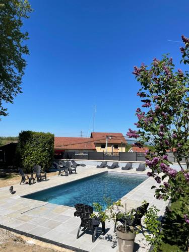 a swimming pool with chairs and tables and a building at Cabane Magique 4 Personnes in La Bâtie-Montgascon