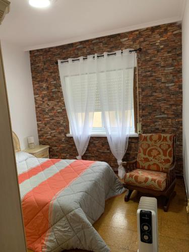 a bedroom with a bed and a window and a chair at A Marosa playa in Burela de Cabo