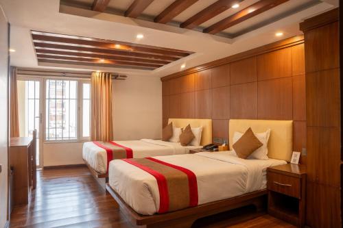 a hotel room with two beds and a window at Hotel Kailash Kutee in Kathmandu