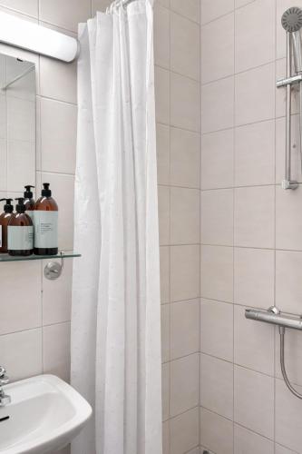 a white bathroom with a shower curtain and a sink at Storebaug Motell in Moss