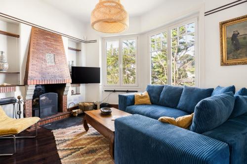 a living room with a blue couch and a fireplace at LA PINÈDE - Villa 4 étoiles vue mer - Plage à 30 m - Emplacement exceptionnel in Dinard