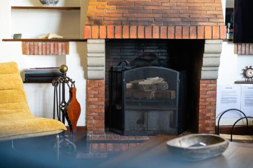 a brick fireplace in a living room with a chair at LA PINÈDE - Villa 4 étoiles vue mer - Plage à 30 m - Emplacement exceptionnel in Dinard