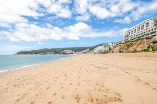 a beach with footprints in the sand and buildings at GuestReady - Beachfront Studio in Sesimbra