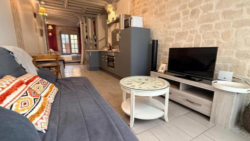 a living room with a couch and a tv and a table at Le Nid de la Loire - Centre historique - 4 pers - Classé 3 étoiles in Blois