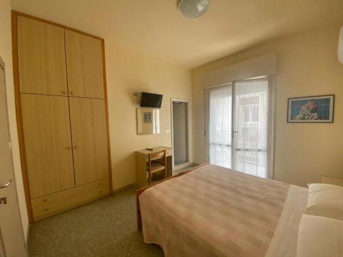 ein Schlafzimmer mit einem Bett, einem Schrank und einem Fenster in der Unterkunft Hotel Soave in Cervia