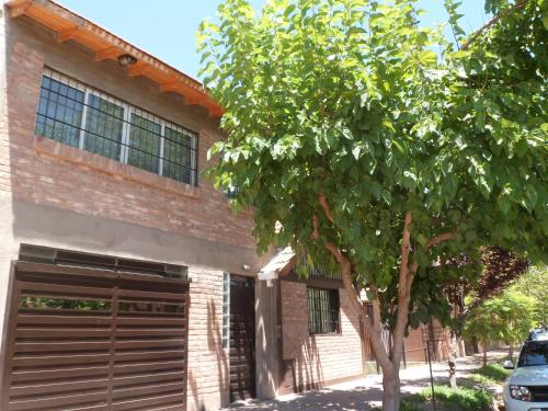 a house with a tree in front of a garage at Monoambiente Luminoso y Tranquilo in Mendoza