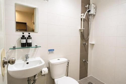 a bathroom with a toilet and a sink and a shower at Obrero Suites Davao in Davao City