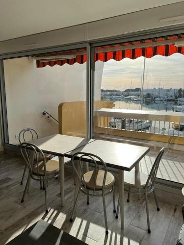 a table and chairs in a room with a window at La Marina de Lairan 2 chambres terrasse vue Port de Plaisance in Le Grau-du-Roi