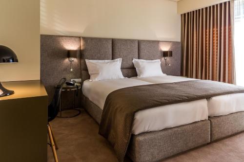 a bedroom with a large bed with two lamps at 4615 Hotel in Felgueiras