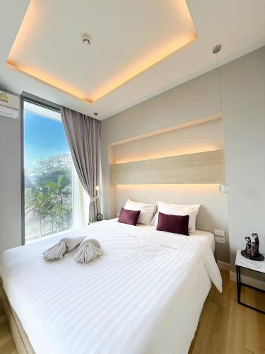 a bedroom with a large white bed with a window at Breezy Condo in Aonang in Ao Nang Beach