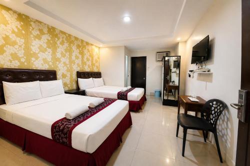 a hotel room with two beds and a desk at Obrero Suites Davao in Davao City