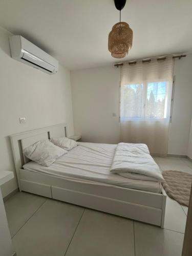 a bed in a white room with a window at Maison mitoyenne in Gignac-la-Nerthe