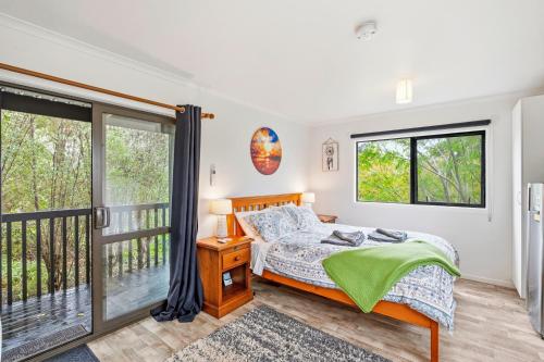 a bedroom with a bed and a balcony at Country Nirvana in Pataua