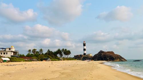 a beach with a lighthouse in the ocean with people on it at Eevara Beach By Shore in Kaup