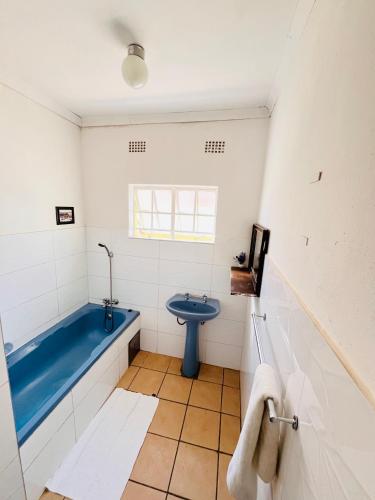 a bathroom with a blue tub and a toilet at Clock Inn Self Catering Accommodation in Gaborone