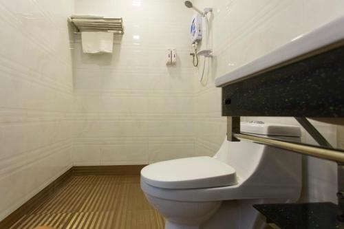 a white bathroom with a toilet and a phone at Aloha Hotel SDN BHD in Pontian Kecil