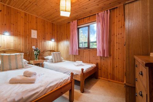 two beds in a room with wooden walls at E29 -Lawnside in Truro