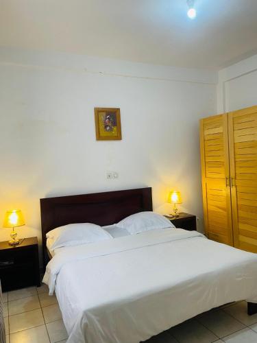 a bedroom with a large white bed with two lamps at HD Luxury Apparts in Yaoundé