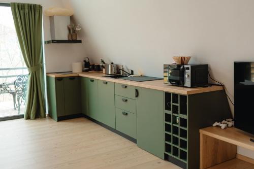 eine Küche mit grünen Schränken und einer Theke mit Mikrowelle in der Unterkunft Fox Cabins in Trăisteni