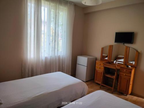 a bedroom with two beds and a desk and a television at Guesthouse MIRAJ - SHABLA in Shabla