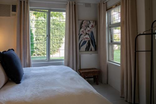 a bedroom with a bed and two windows at Eunoia Cottage in Paarl