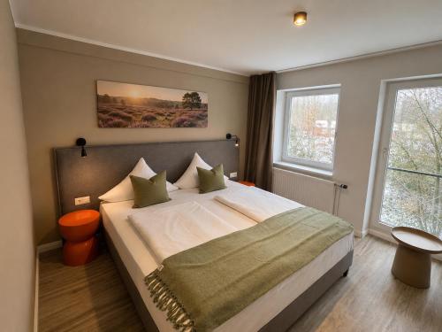 a bedroom with a large bed and two windows at UNO Smart Soltau Wietzendorf in Soltau