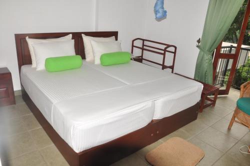 1 dormitorio con 1 cama con almohadas verdes y blancas en KANDY Holiday Residence, en Kandy