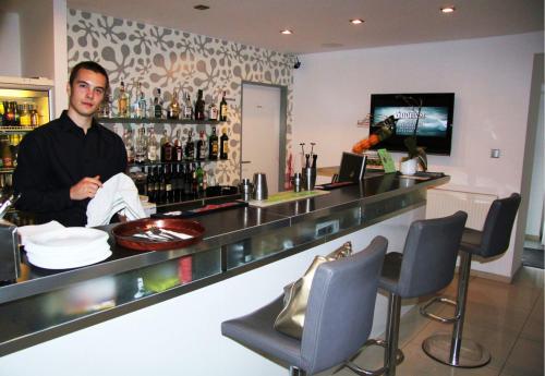 a man standing behind a bar in a restaurant at Villa Green in Sliač